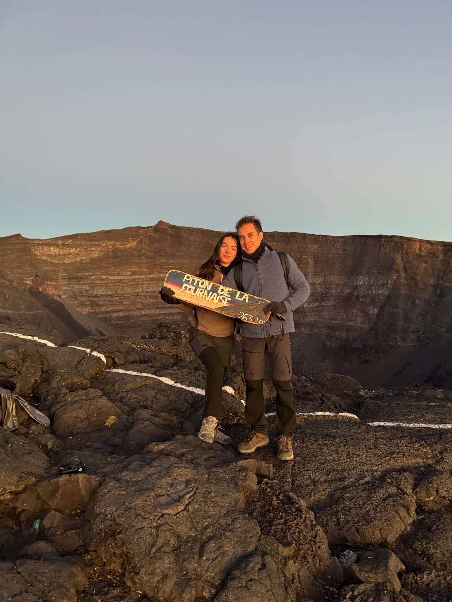 Élise et Rémi au sommet du Piton de la Fournaise, devant le cratère, avec le panneau du sommet.